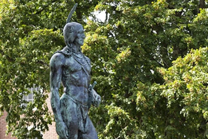 A bronze statue of a Native American man.