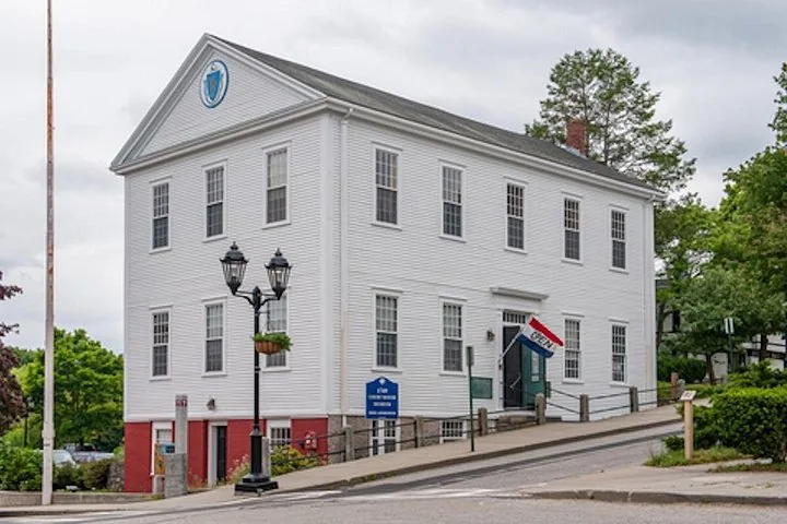 A white two-story building with a blue sign.